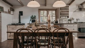 Cocina con una isla central, sillas de madera, luces colgantes, estufa y ventana con vistas.