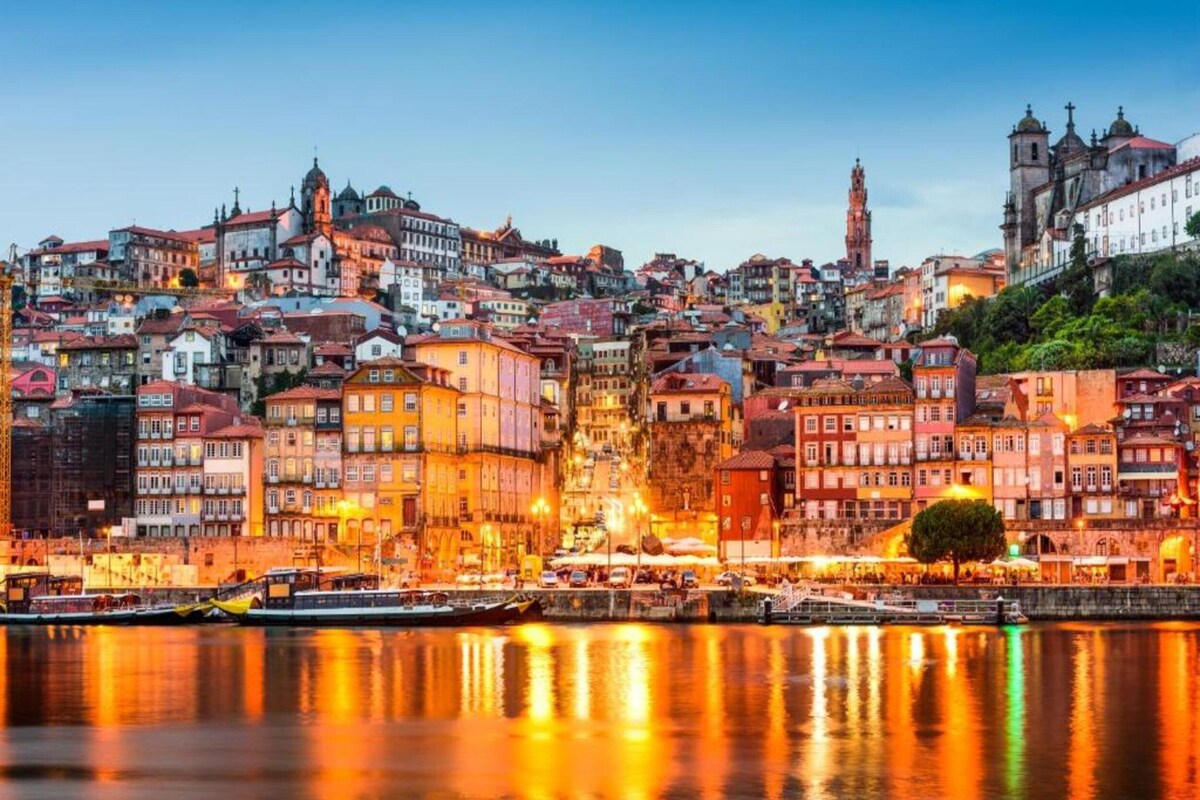 Paisagem urbana com edifícios históricos, um rio e uma torre imponente.