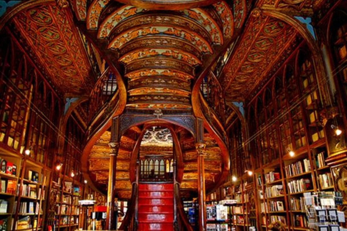 A grand library with ornate wooden ceilings and bookshelves filled with books.