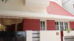 A modern house with a red roof, a white facade, and a gated entrance.