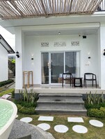 Ein modernes Gebäude mit überdachter Veranda, Pool und einem Garten mit trittfesten Steinen.