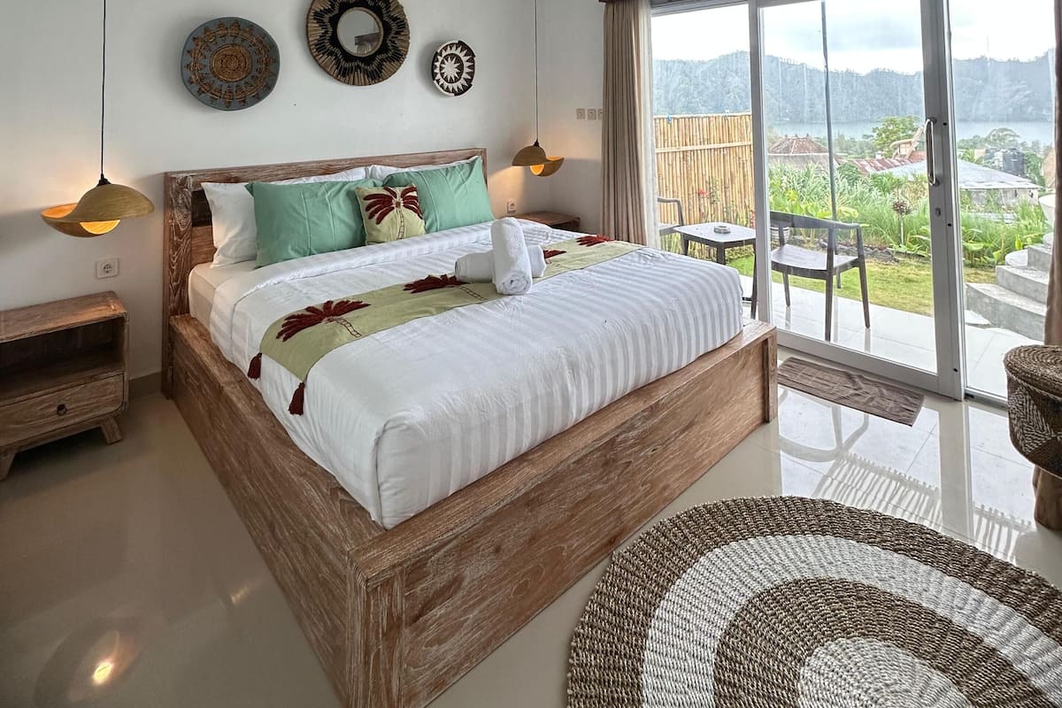 A bedroom with a wooden bed, a view of the outdoors, and decorative wall art.