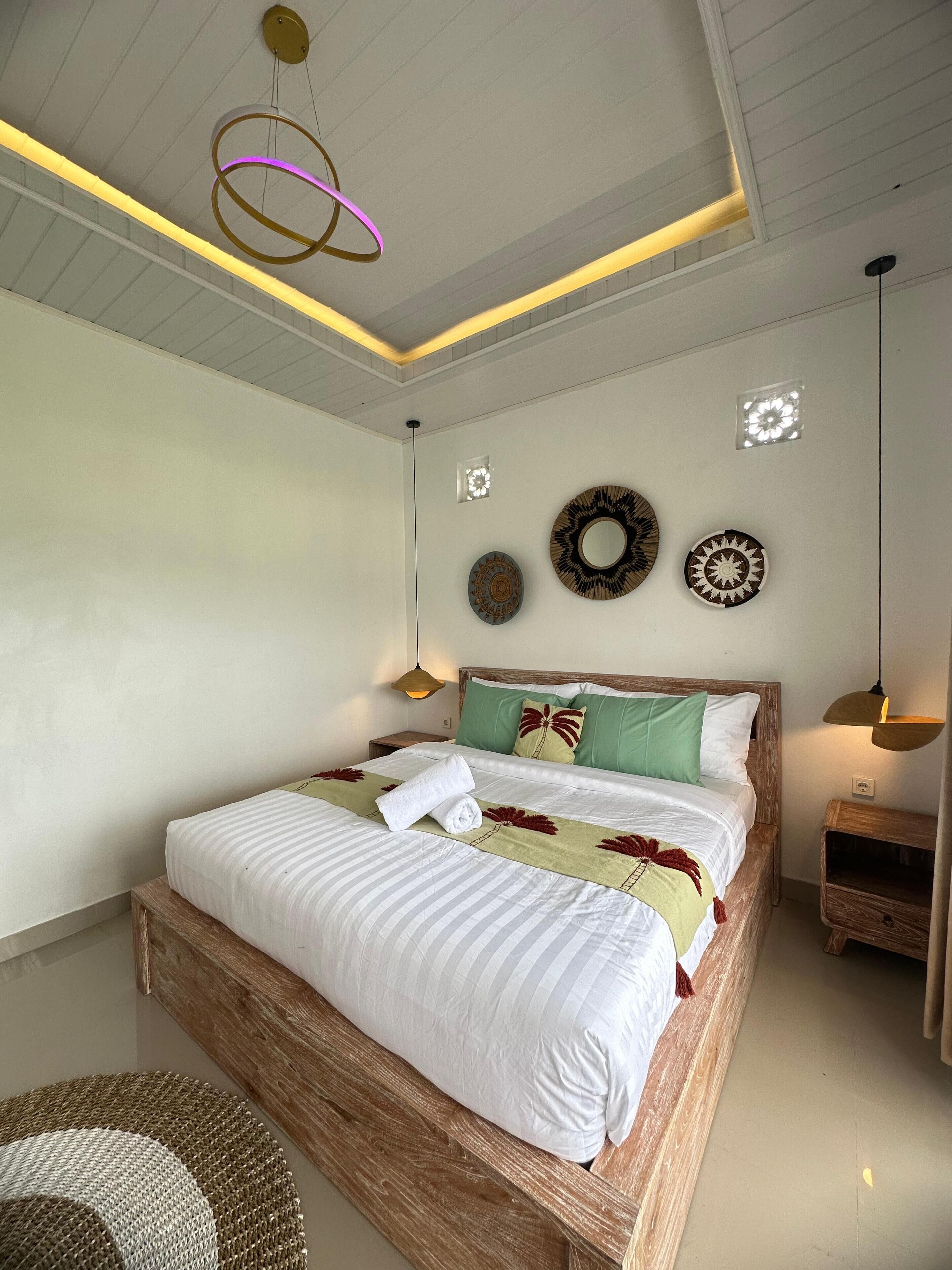 Un lit bien fait, avec une tête de lit en bois, une table de chevet et une lampe suspendue.
