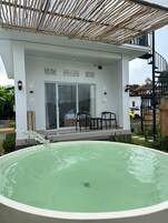 Un patio techado con un jacuzzi, puerta corrediza de vidrio y mobiliario exterior.