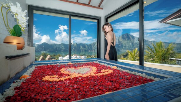 A room with a large window, a tiled floor with a flower pattern, and a view of mountains and a lake.