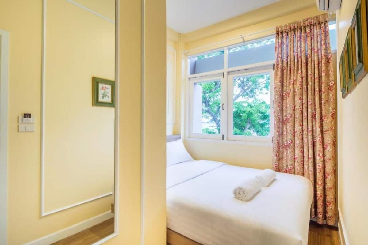 A bedroom with a bed, a window with curtains, and a door.
