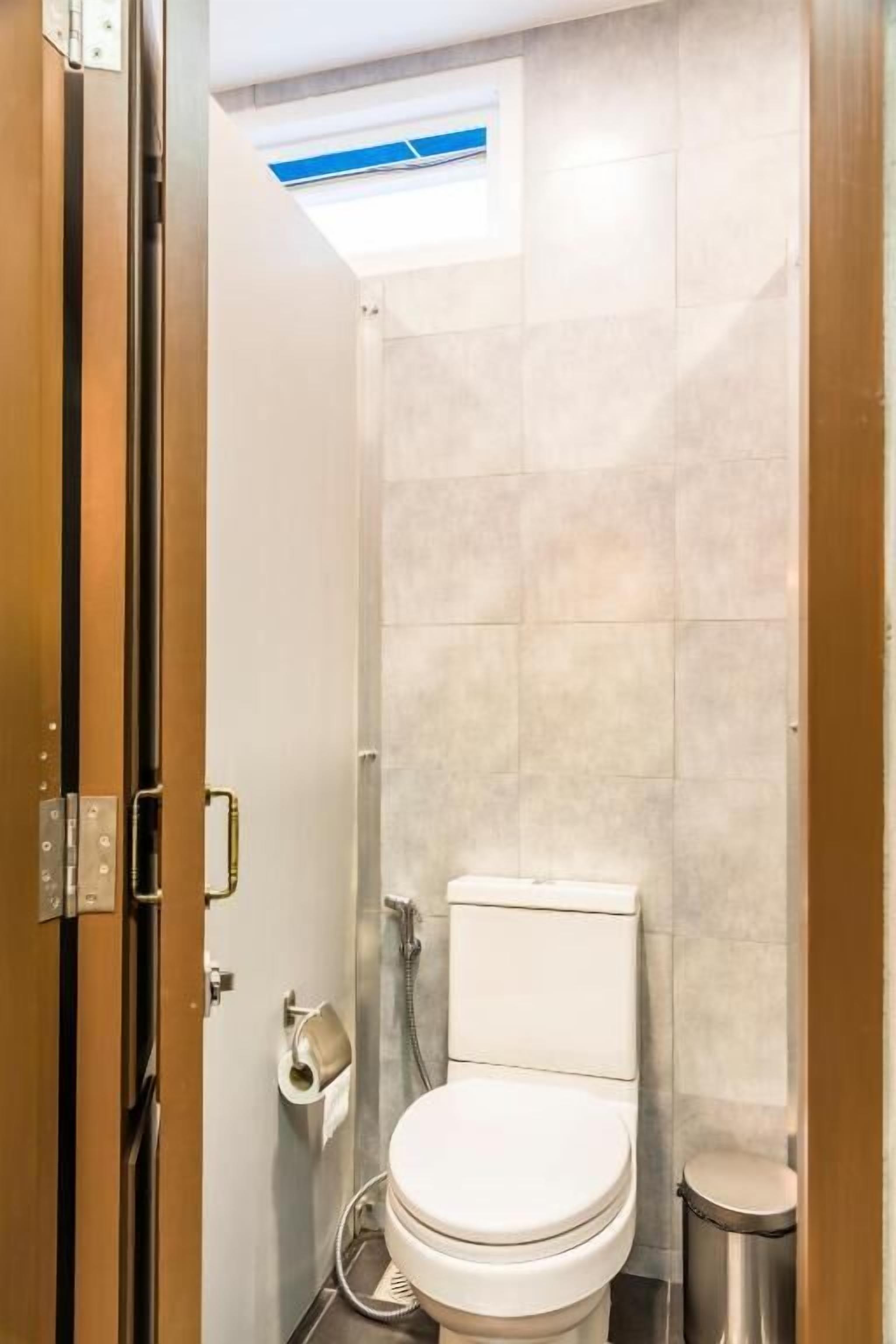 A compact bathroom with a toilet, a small trash bin, and a shower area.