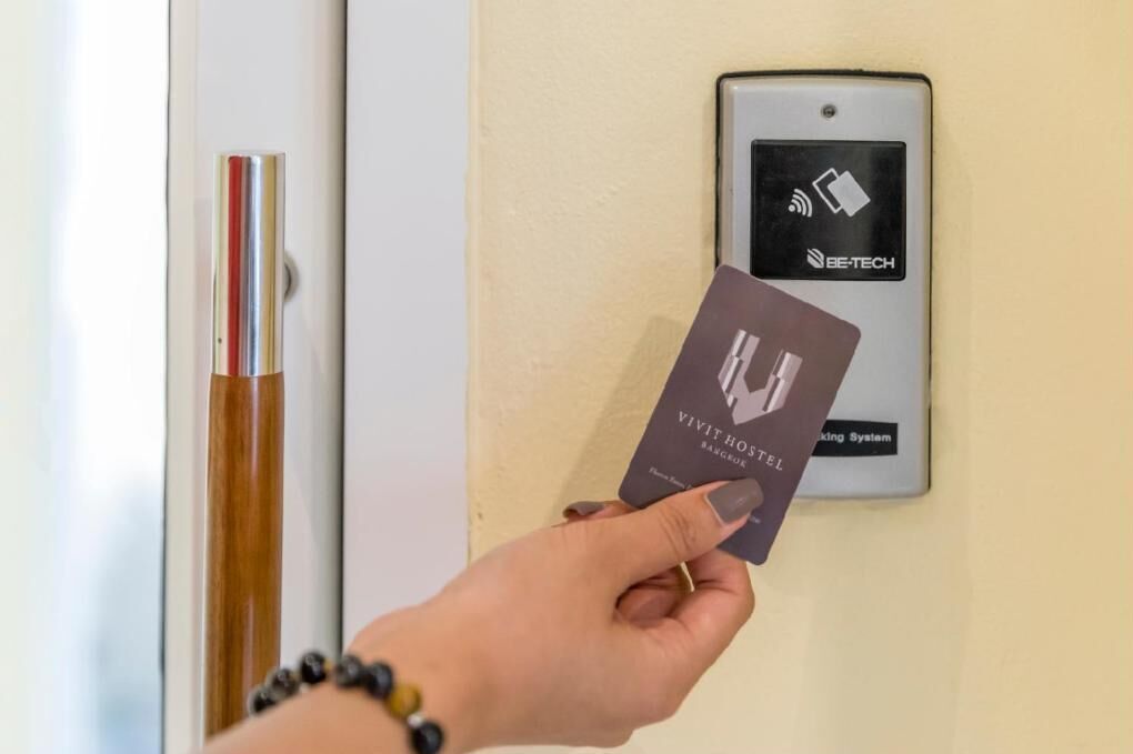 Una mano sosteniendo una tarjeta frente a un cierre de puerta biométrico con el logotipo de BE-TECH.