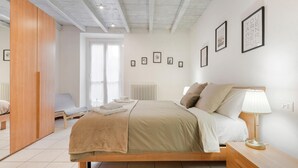 Une chambre à coucher avec un lit, une table de chevet, une lampe et des tableaux encadrés accrochés au mur.