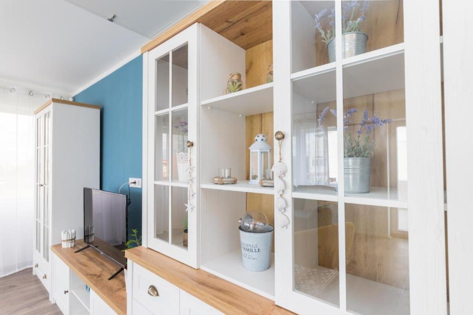 A modern living room with a TV, wooden cabinets, and a blue accent wall.