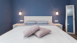 Un dormitorio con una cama grande, dos mesitas de noche y un espejo de cuerpo entero.