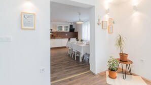 Una cocina moderna con armarios blancos, un comedor con sillas blancas y una planta en maceta.