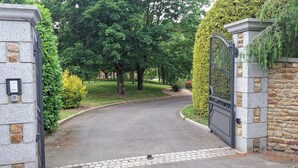 A gated driveway leading to a building with stone walls and a metal gate. - B&B Baie du Mont Saint-Michel (Le Val-Saint-Père)