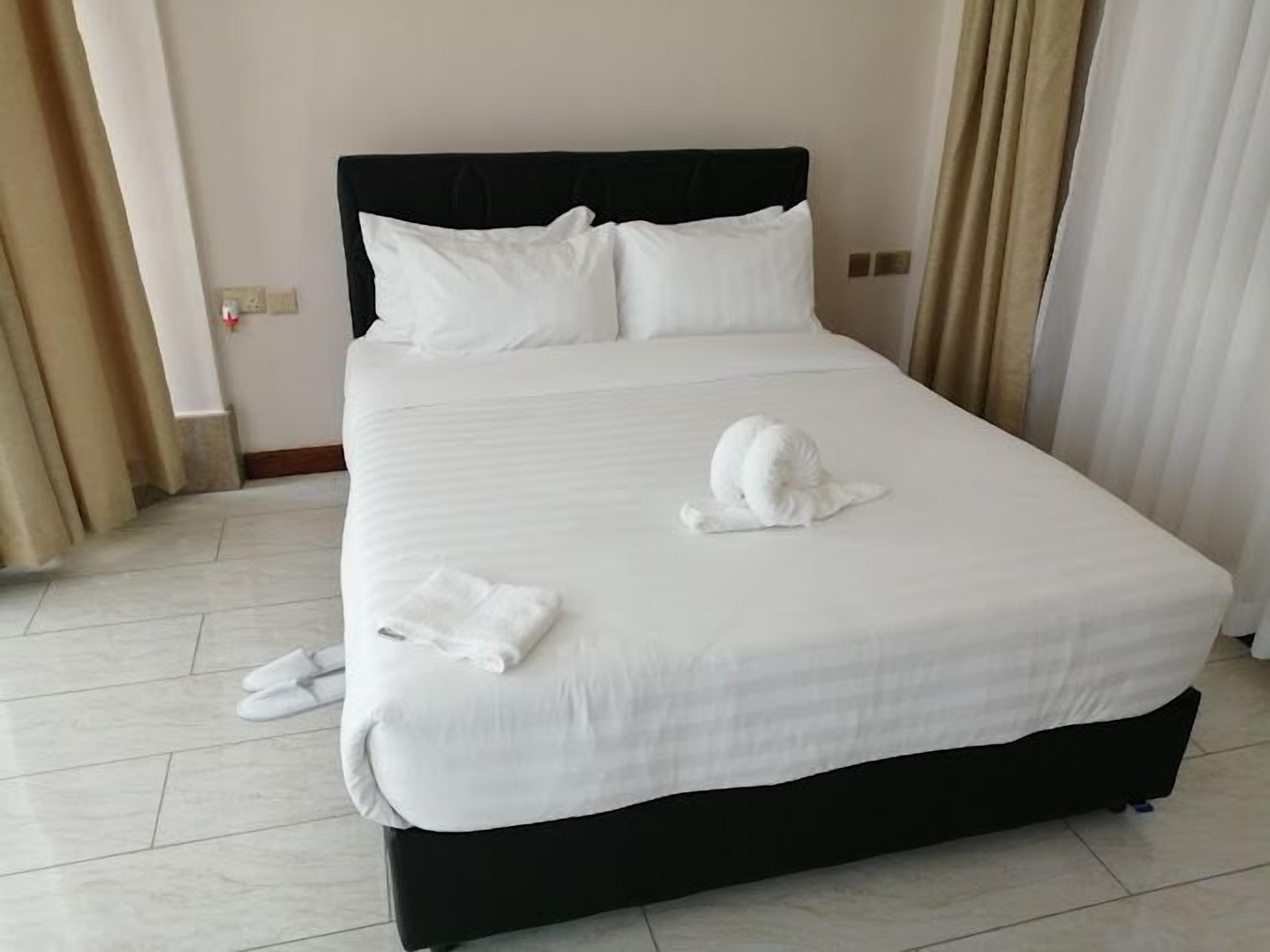 Habitación de hotel con una cama grande, ropa de cama blanca y un cabecero negro.