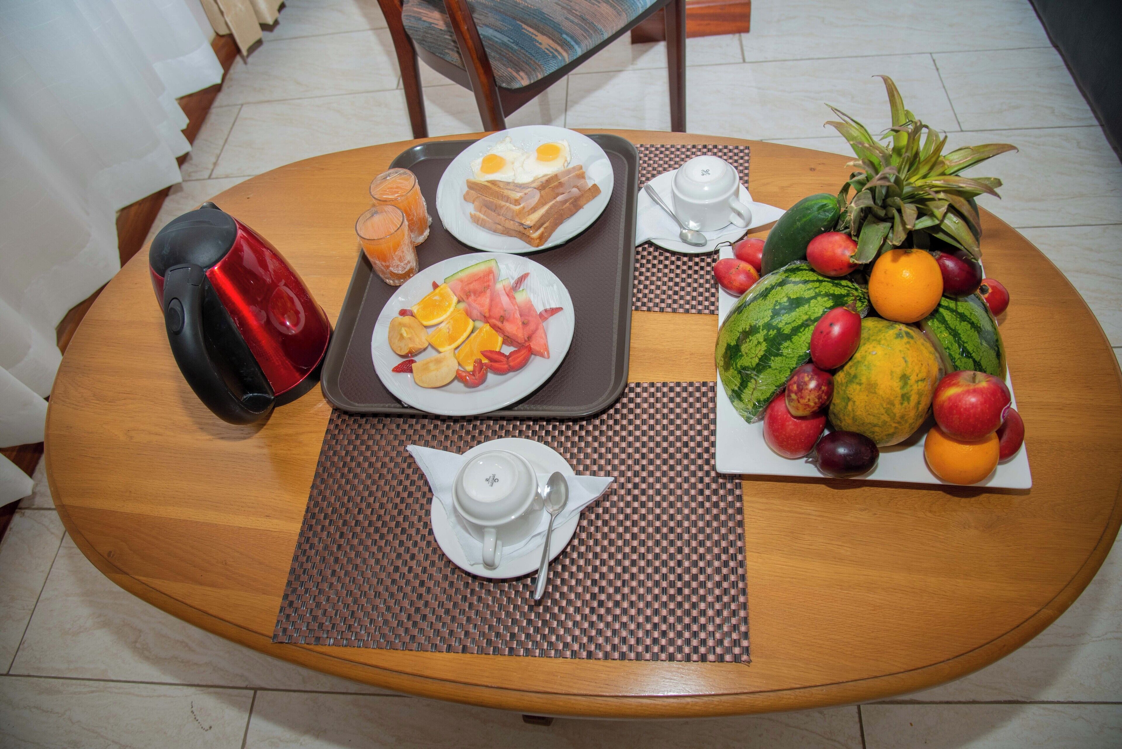 A breakfast tray with eggs, toast, and fruit on a wooden table.