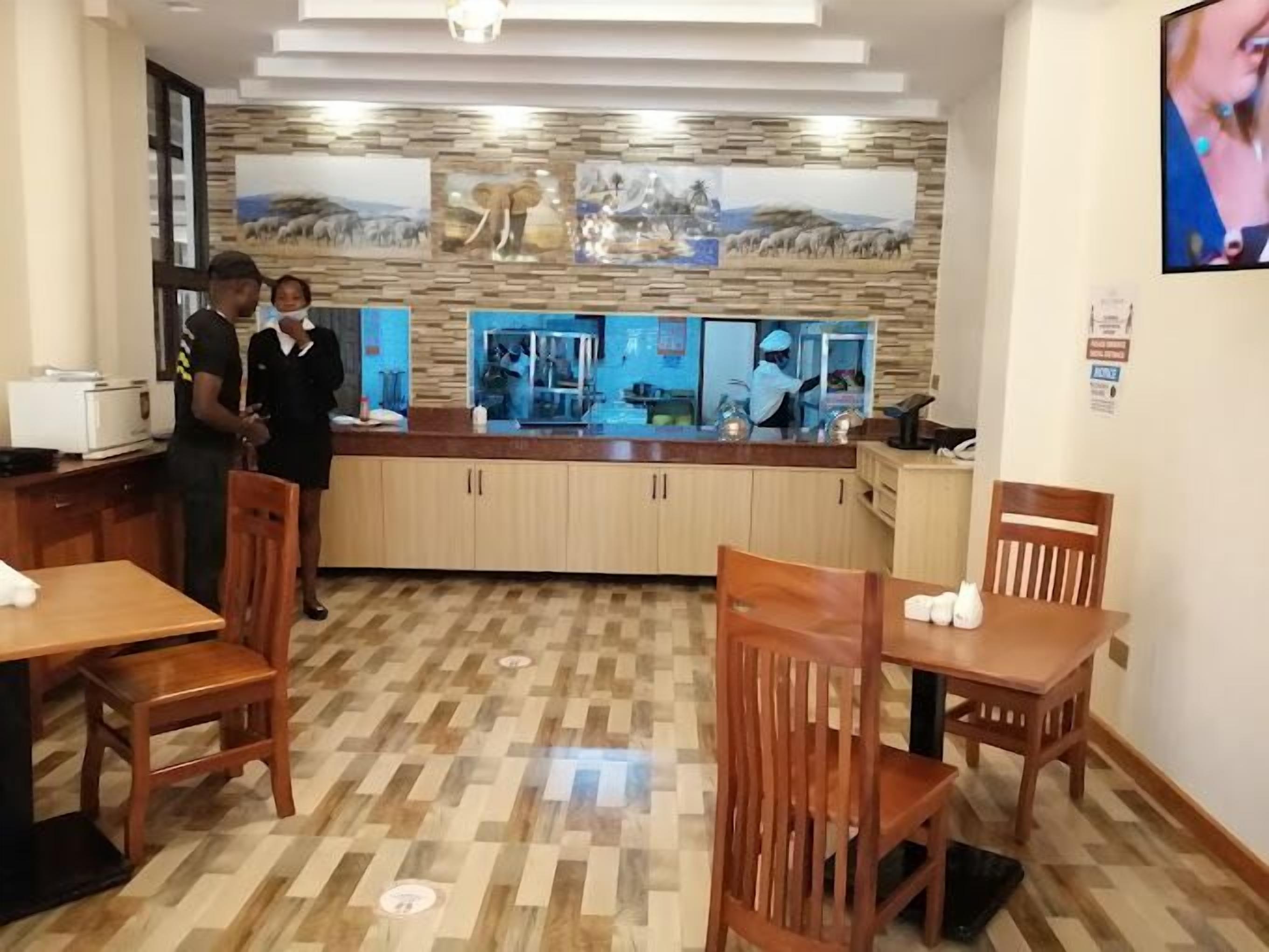 Un restaurante con muebles de madera, una barra con mostrador de vidrio y una pared con cuadros enmarcados.