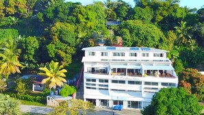 Un hotel de varios pisos con balcones, rodeado de abundante vegetación.