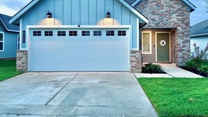 A two-story house with a blue garage and a stone front. - GIG ’EM LANE • 3BR • Grill & Fire Pit • Coffee Bar • 75" TV • Near Hwy 6 (College Station)