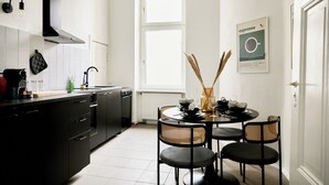 Moderni keittiö, jossa on mustat kaapit, musta liesi ja ruokailutila, jossa on pyöreä pöytä ja neljä tuolia.