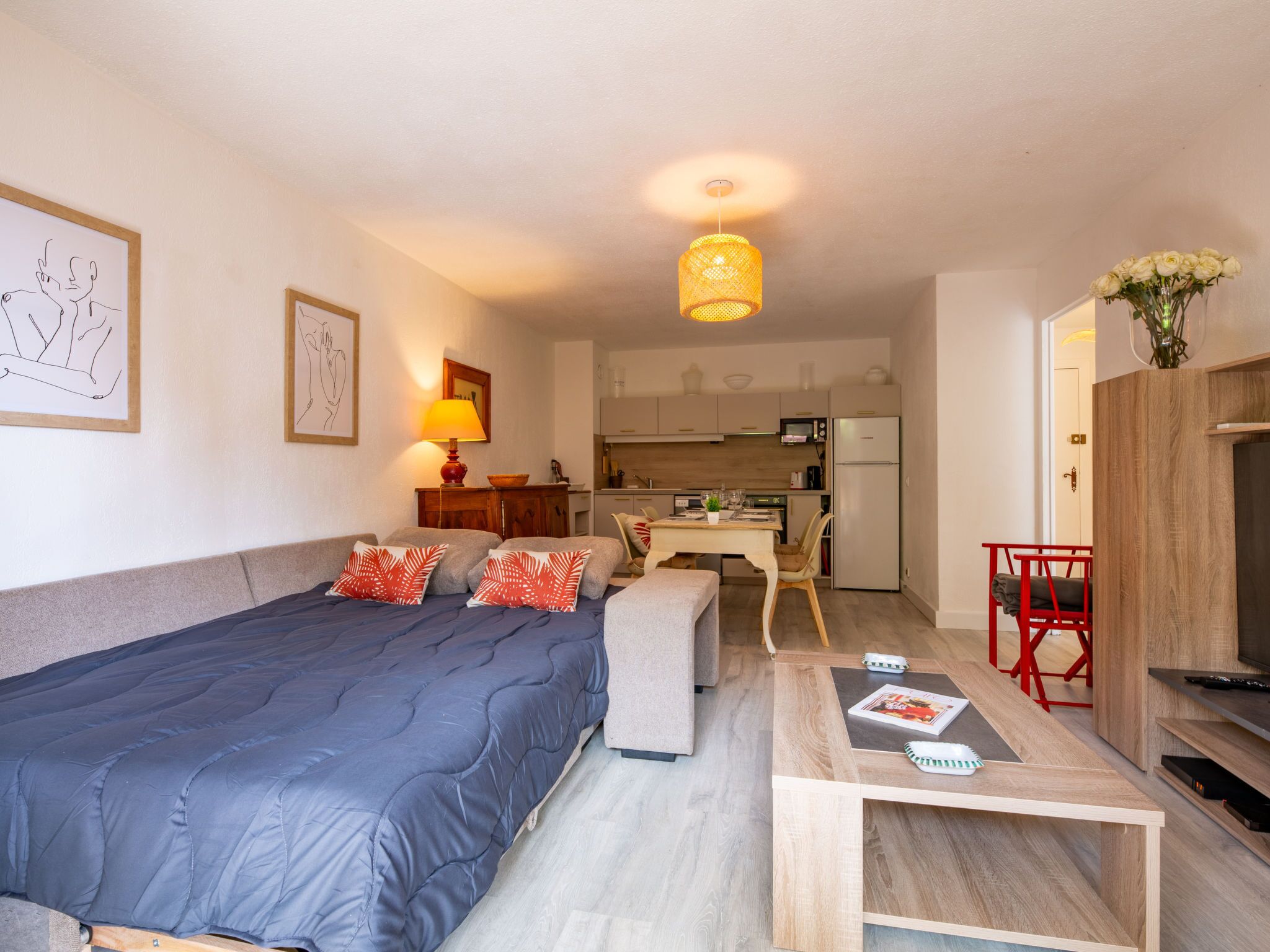 Een moderne, compacte woonruimte met een bed, een eethoek en een kitchenette.