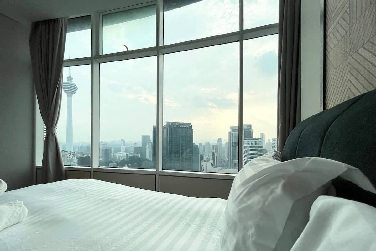 A hotel room with a large window offering a cityscape view, including a prominent tower.