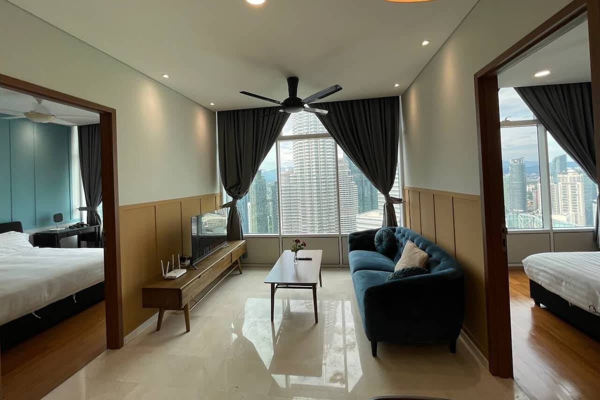 A modern hotel room with a bed, a sofa, a coffee table, and a TV.