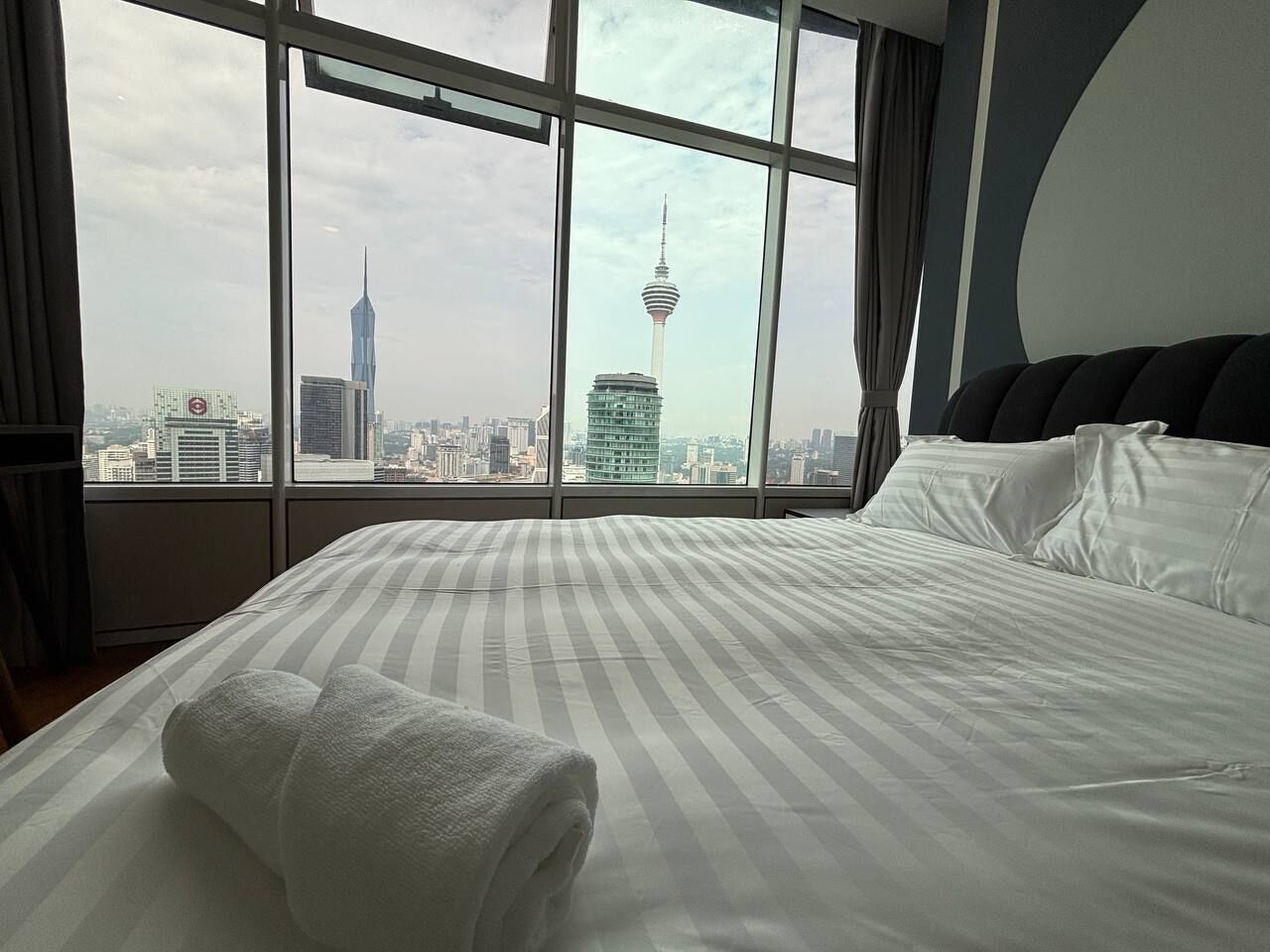 Une chambre d’hôtel dotée d’une grande fenêtre donnant sur le panorama de la ville, avec une vue imprenable sur une tour emblématique.