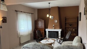 A living room with a sofa, a fireplace, a wooden cabinet, and a ceiling fan.