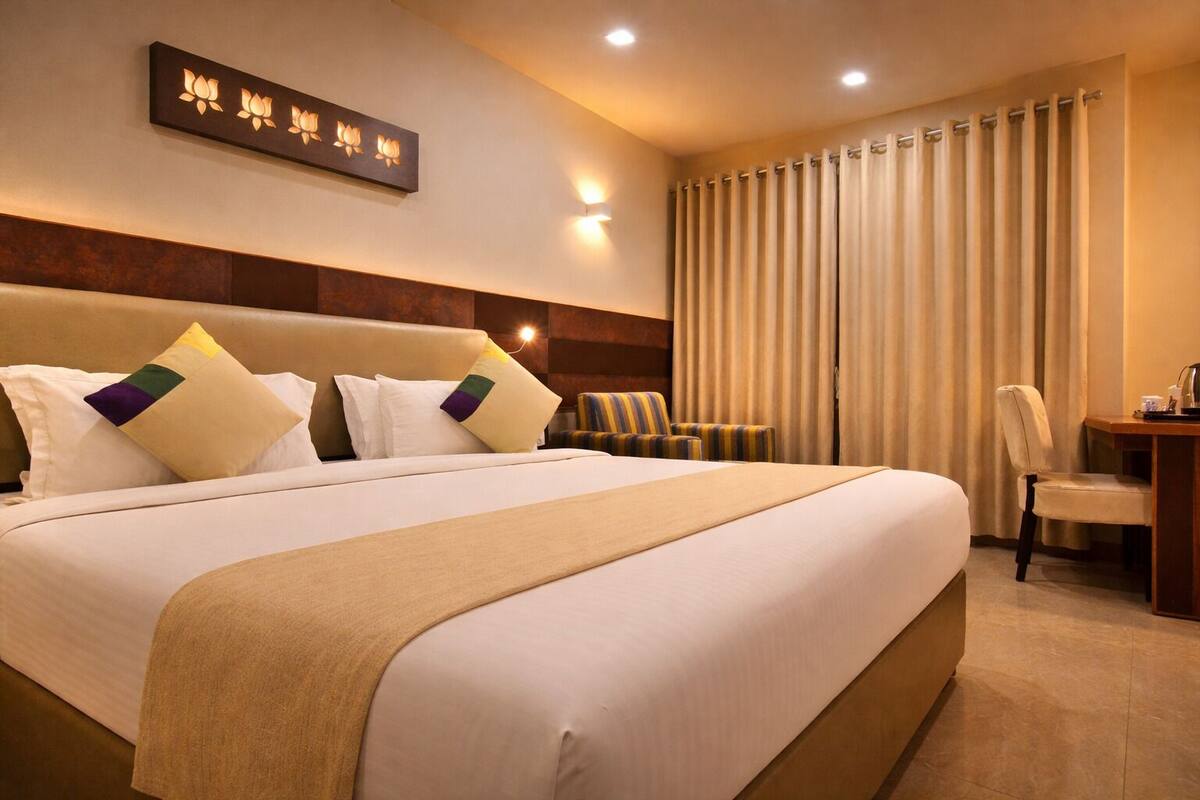 Habitación de hotel con una cama grande, un escritorio, una silla y un aplique de pared.
