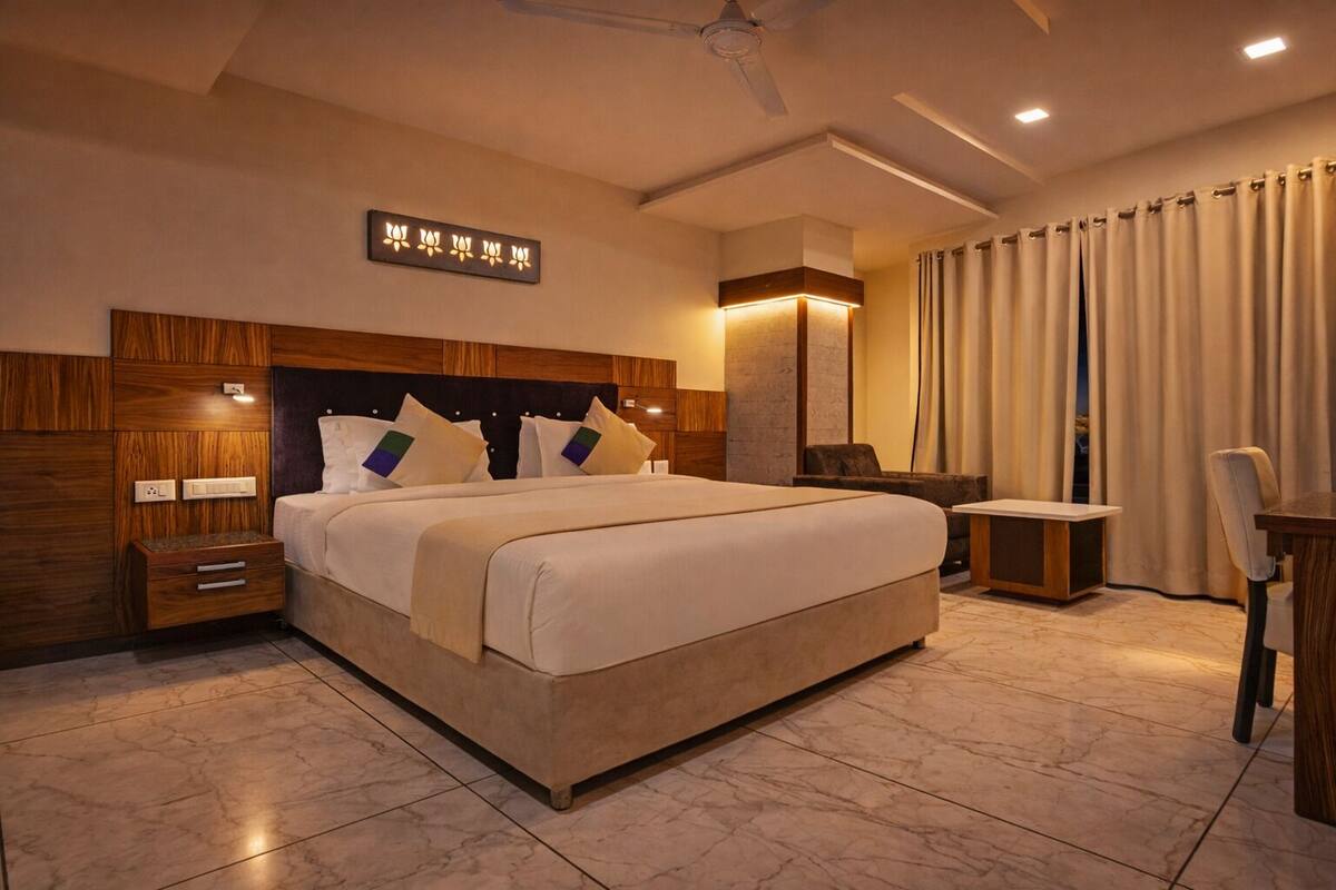 Una habitación de hotel moderna con una cama grande, una mesita de noche, una silla, un escritorio y un ventilador de techo.