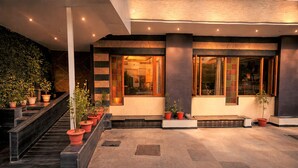 A modern building with a staircase, potted plants, and a well-lit entrance. - Hotel Mandovin - A Premium Hotel In Udaipur (Udaipur)