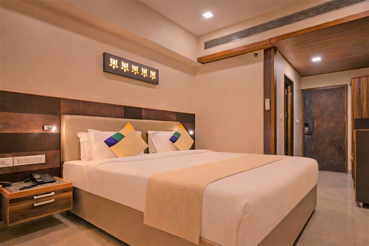 Une chambre d’hôtel avec un grand lit, une table de chevet et un luminaire fixé au mur.