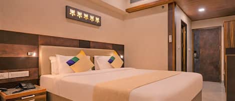 Une chambre d’hôtel avec un grand lit, une table de chevet et un luminaire fixé au mur.