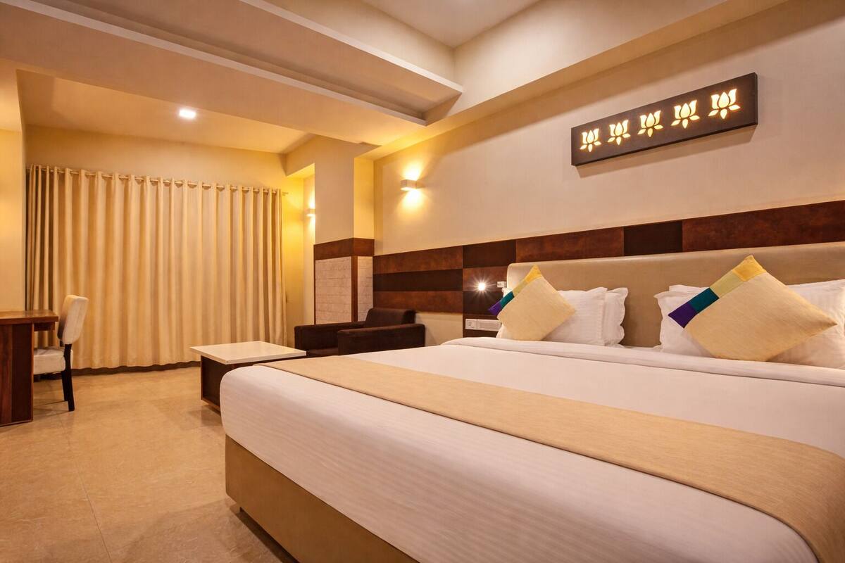 Habitación de hotel con una cama grande, un escritorio, una silla y una lámpara fijada a la pared.