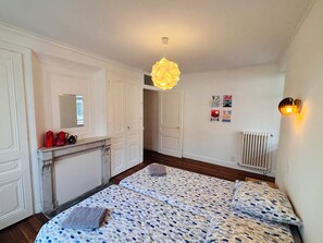 A bedroom with a bed, a dresser, a mirror, and a radiator. - Gite du Canal at the foot of the Grand Colombier - Ideal for large groups! (Artemare)
