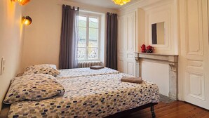 Ein Schlafzimmer mit Doppelbett, einem fenster mit Vorhängen, einem Kamin und zwei Wandlampen.