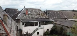 Un bâtiment doté d’un toit en pente, d’une cheminée et d’un escalier menant à un balcon.