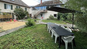 Ein Innenhof mit Esstisch und Stühlen, einer Schaukel und einer Treppe, die zu einer zweiten Etage führt.