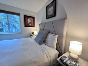 Une chambre d’hôtel avec un lit, une table de chevet, une lampe et un tableau encadré au mur.