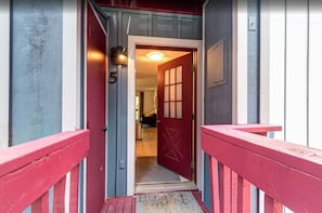 Puerta roja con el número 5 sobre ella, que da paso a una habitación con cama y ventana.