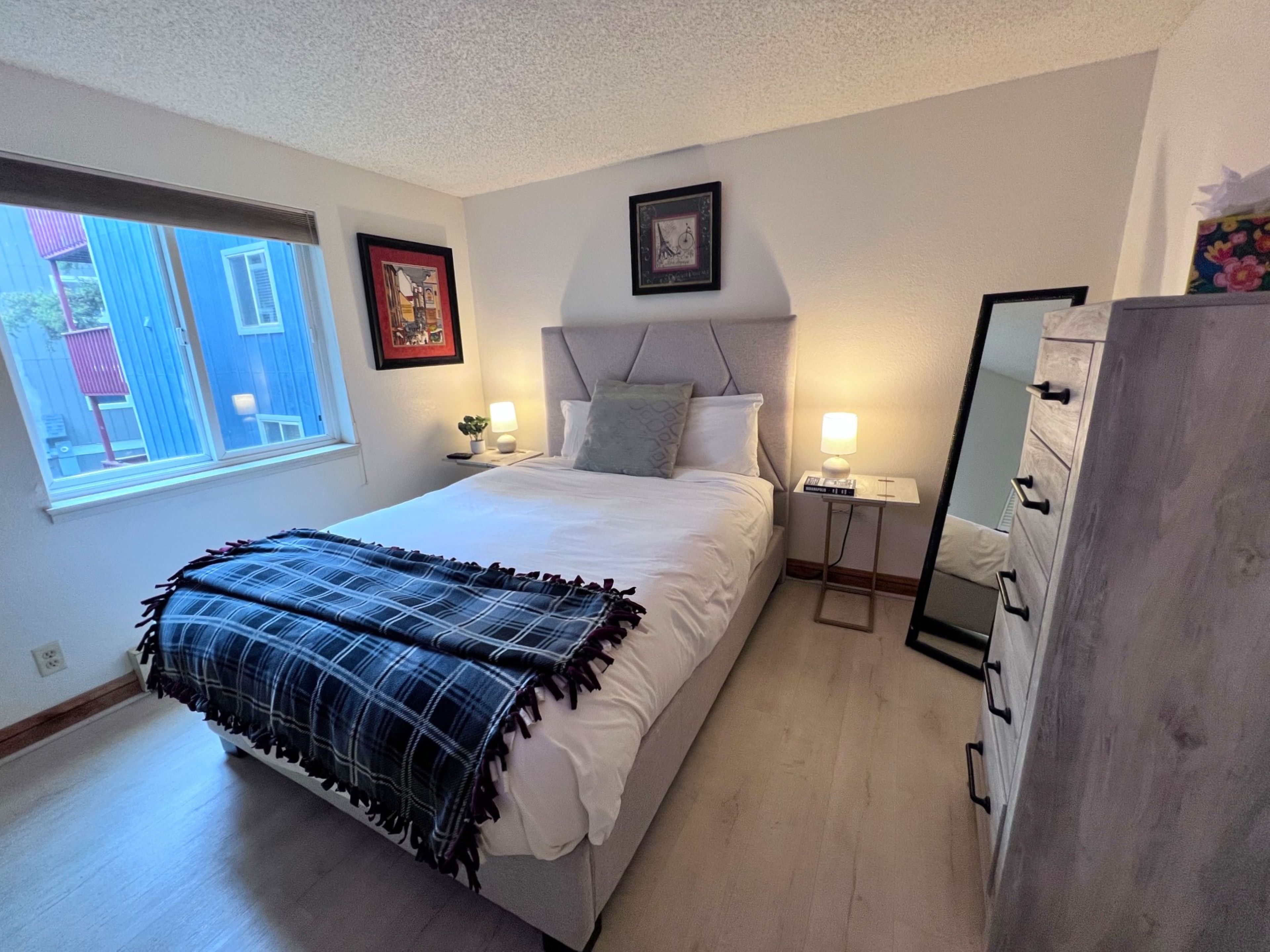 Une chambre à coucher avec un lit, des tables de chevet, un miroir et une commode.