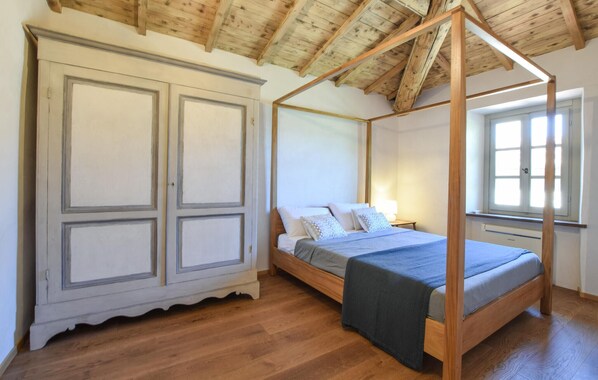 Une chambre à coucher avec un lit à baldaquin, une grande armoire et une fenêtre laissant entrer la lumière naturelle.