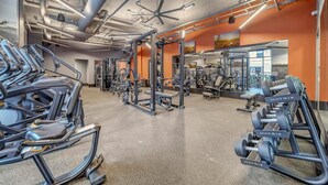 Uma academia com máquinas de cardio, equipamentos de musculação e espelhos nas paredes.