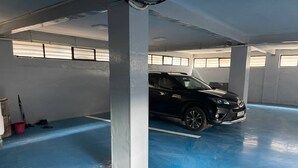 A parking garage with a blue floor, a black car parked, and concrete pillars. - Luxurious 3-bedroom apartment with WiFi in Bole Addis (Addis)