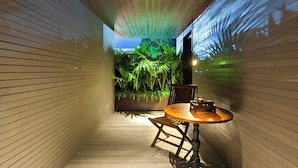 A narrow corridor with wooden panel walls, a round wooden table with chairs, and a view of lush greenery outside. - ANMO Hotle (Xiamen)
