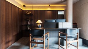 A modern kitchen with dark wooden cabinetry, a central island with a black countertop, and two black chairs. - ANMO Hotle (Xiamen)