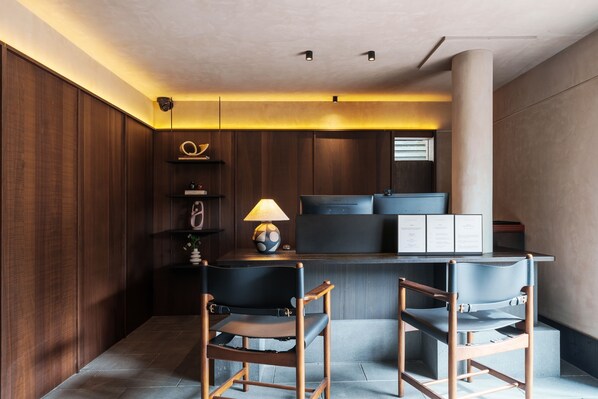 Una cocina moderna con armarios de madera oscura, una isla central con encimera negra y dos sillas negras.