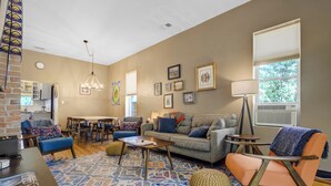 Un salon comprenant un canapé, une table basse et des fauteuils, un tapis à motifs, ainsi qu’un coin repas avec une table et des chaises.