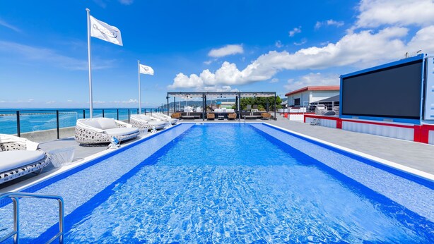 A pool area with lounge chairs and a glass-enclosed seating area. - awaJ Beach Club (Awaji)