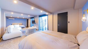 A modern hotel room with a large bed, a sofa, a small table, and a view of the outside. - awaJ Beach Club (Awaji)